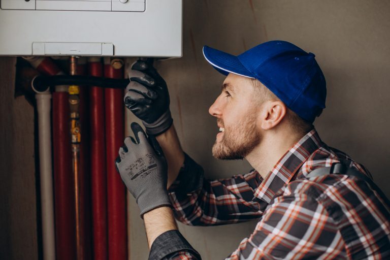 Un technicien chauffagiste Logista Hometech qui répare une chaudière murale