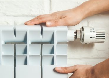 Une homme se chauffe les mains sur un radiateur