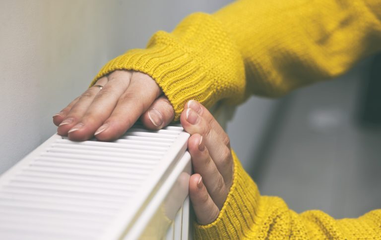Une femme se chauffe les mains sur un radiateur