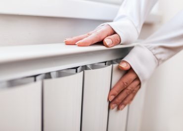 Une femme se réchauffant les mains sur un radiateur