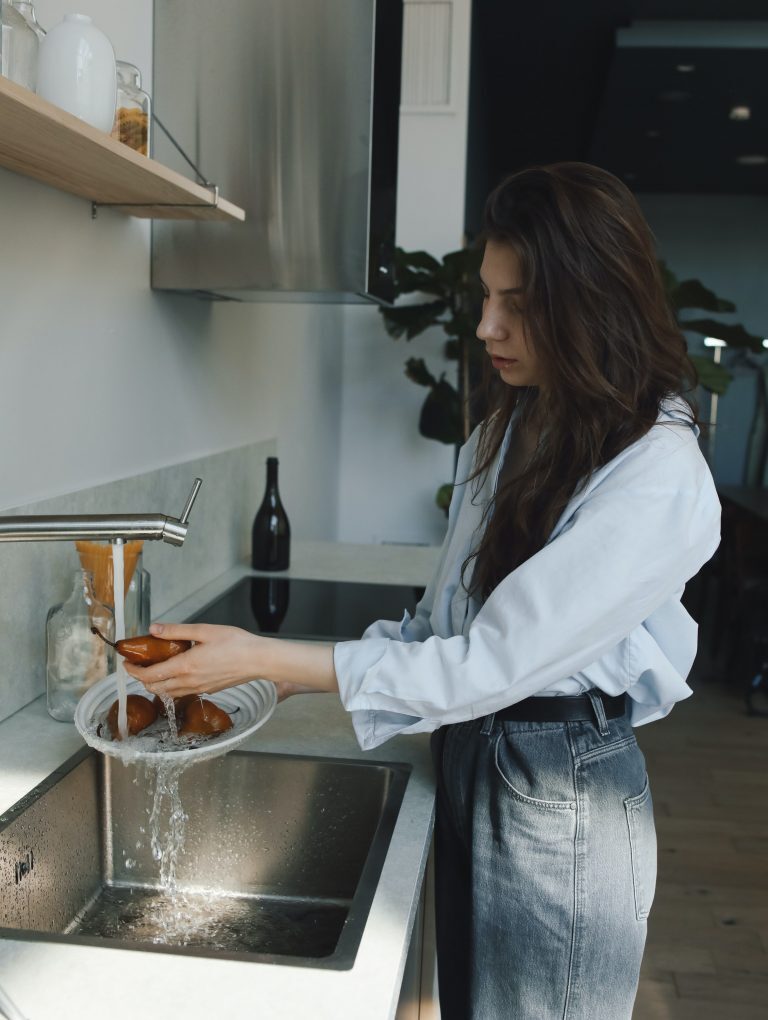 Une femme utilise l'eau du robinet chauffée par un chauffe-eau thermodynamique