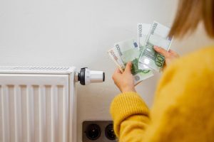 Un radiateur avec une femme tenant les économies réalisé avec les éco-gestes dans la main